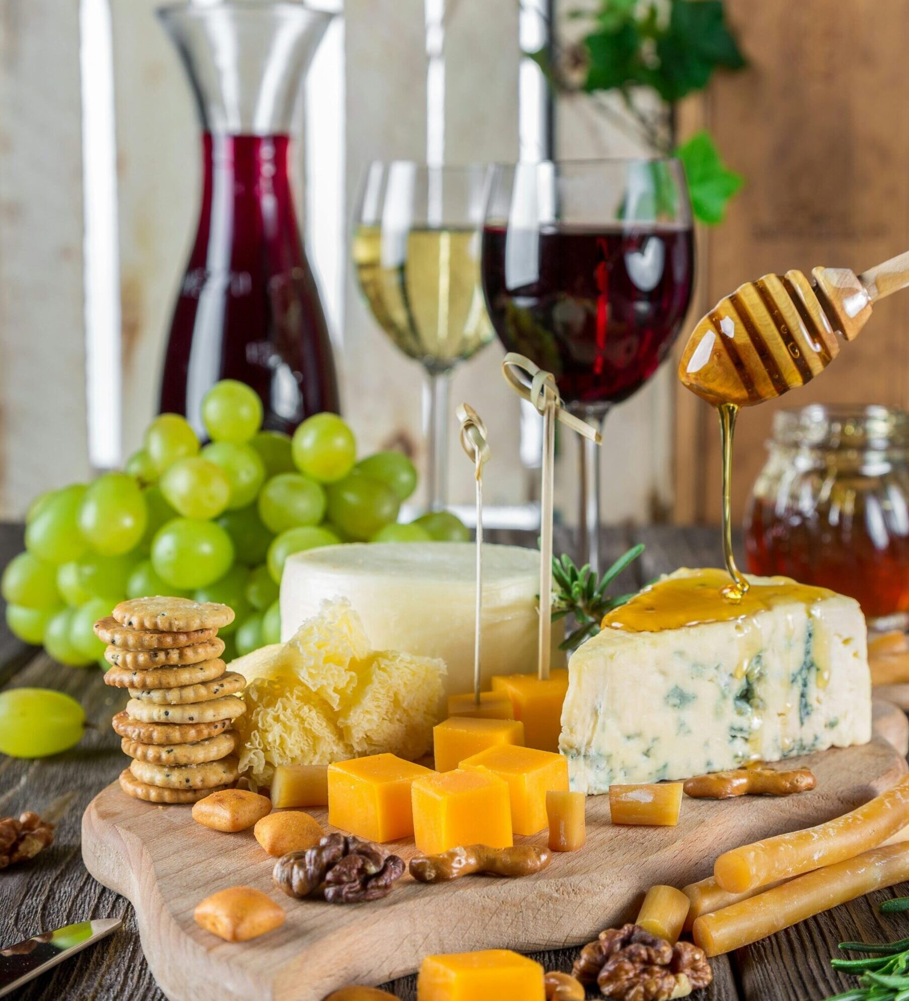 Sophisticated cheese platter with assorted wines, grapes, honey, and nuts.