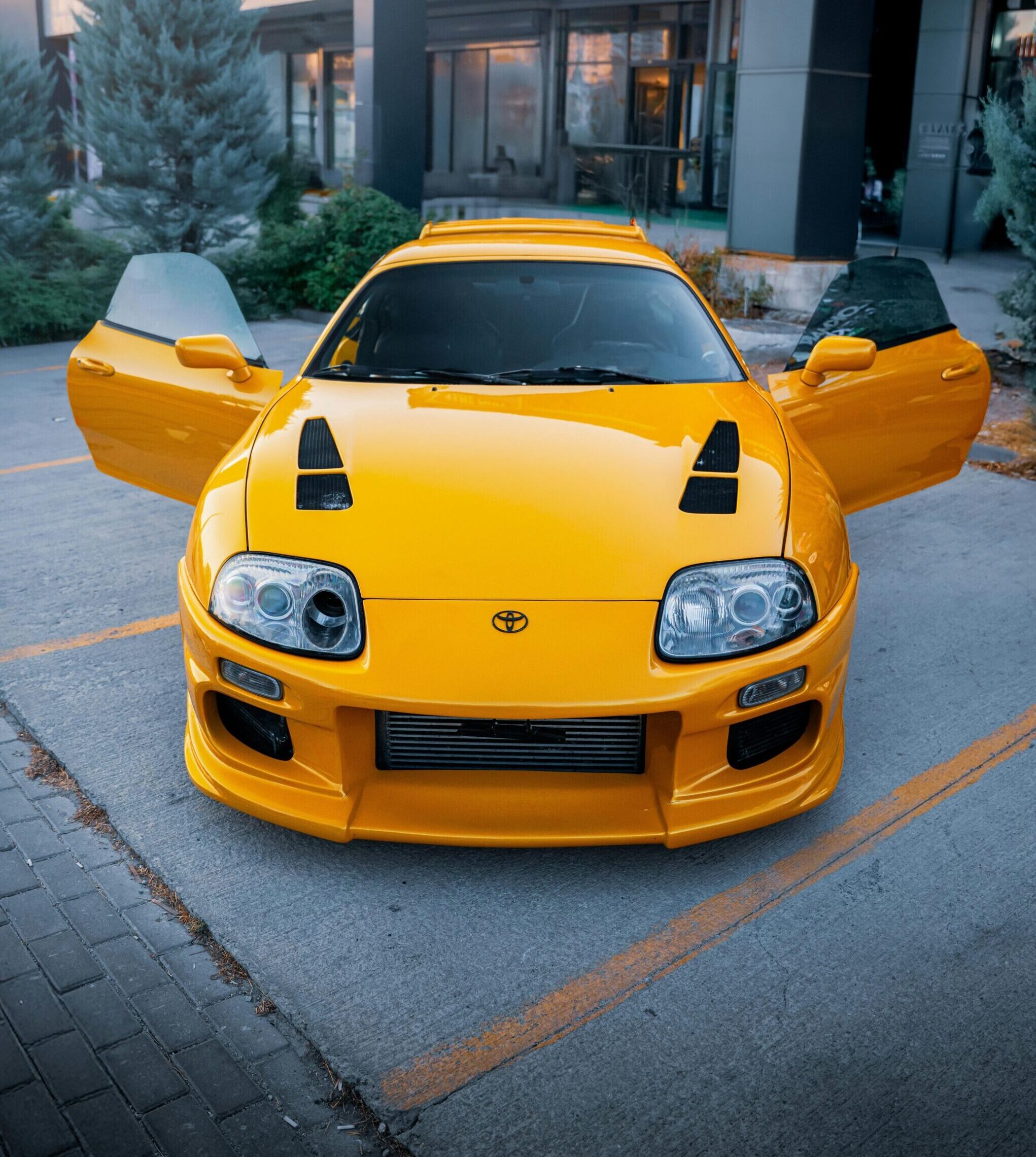 Vibrant yellow Toyota Supra with open doors in an urban setting in Ankara, Türkiye.
